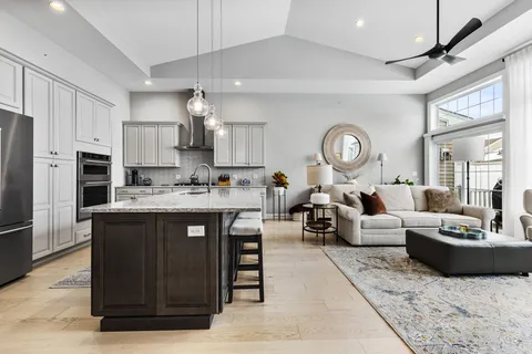 a living room with stainless steel appliances granite countertop a stove a sink dishwasher a dining table and chairs with wooden floor