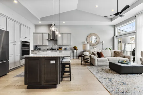 a living room with stainless steel appliances granite countertop a stove a sink dishwasher a dining table and chairs with wooden floor