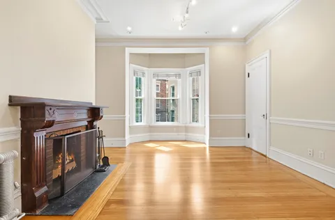 an empty room with wooden floor cabinet and windows