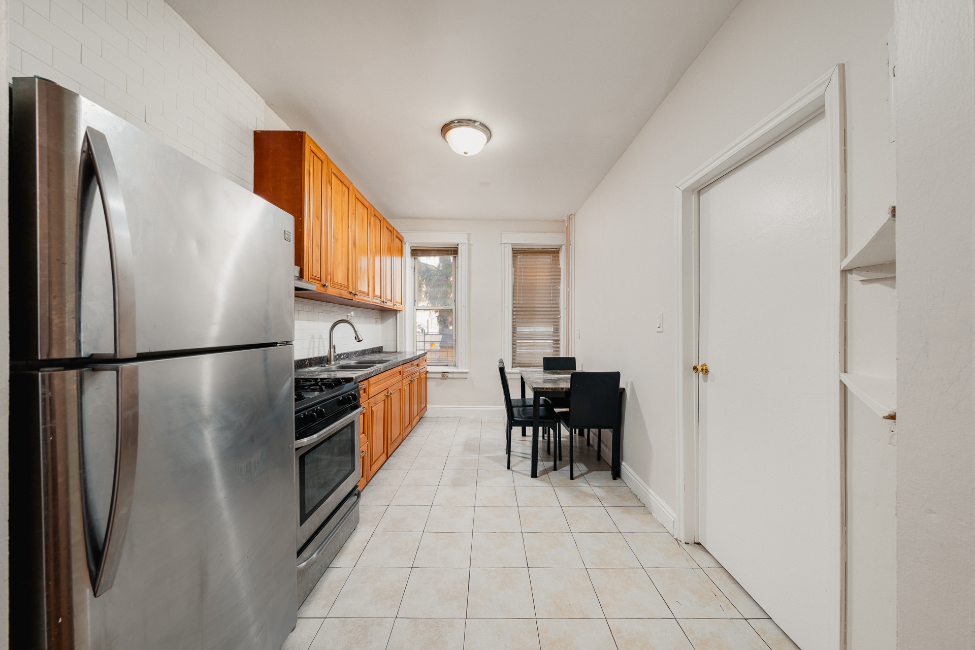 70-03 66th Street, Unit 1L Queens, NY 11385 - Photo 3 of 8 a kitchen with stainless steel appliances granite countertop a refrigerator and a stove top oven