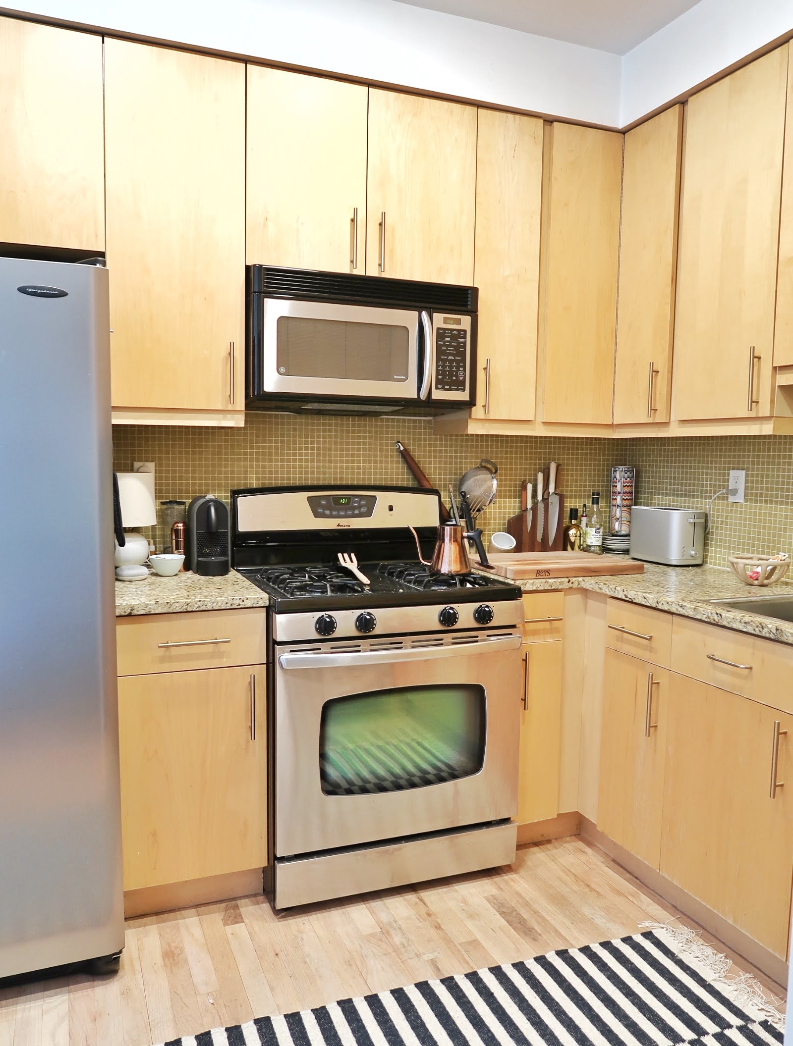 296 East 2nd Street, Unit 4G Manhattan, NY 10009 - Photo 9 of 14 a kitchen with a stove a sink and a white wooden cabinets