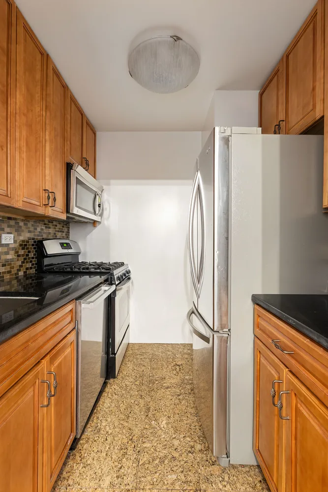 a kitchen with stainless steel appliances granite countertop a refrigerator a stove and a sink with wooden cabinets