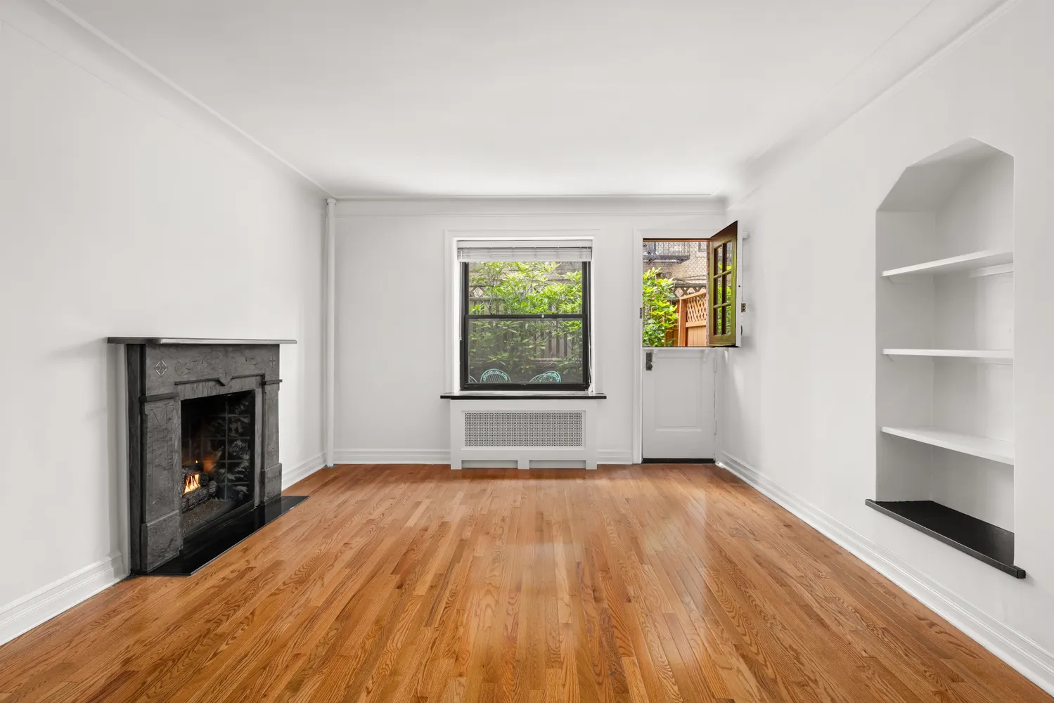 a view of empty room with wooden floor and fireplace
