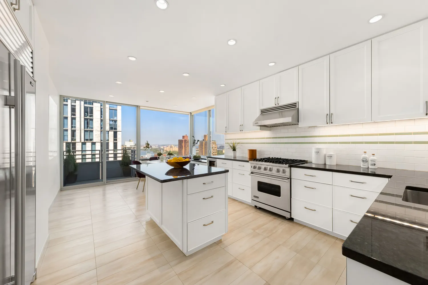 a kitchen with stainless steel appliances granite countertop a stove top oven a sink and white cabinets with wooden floor