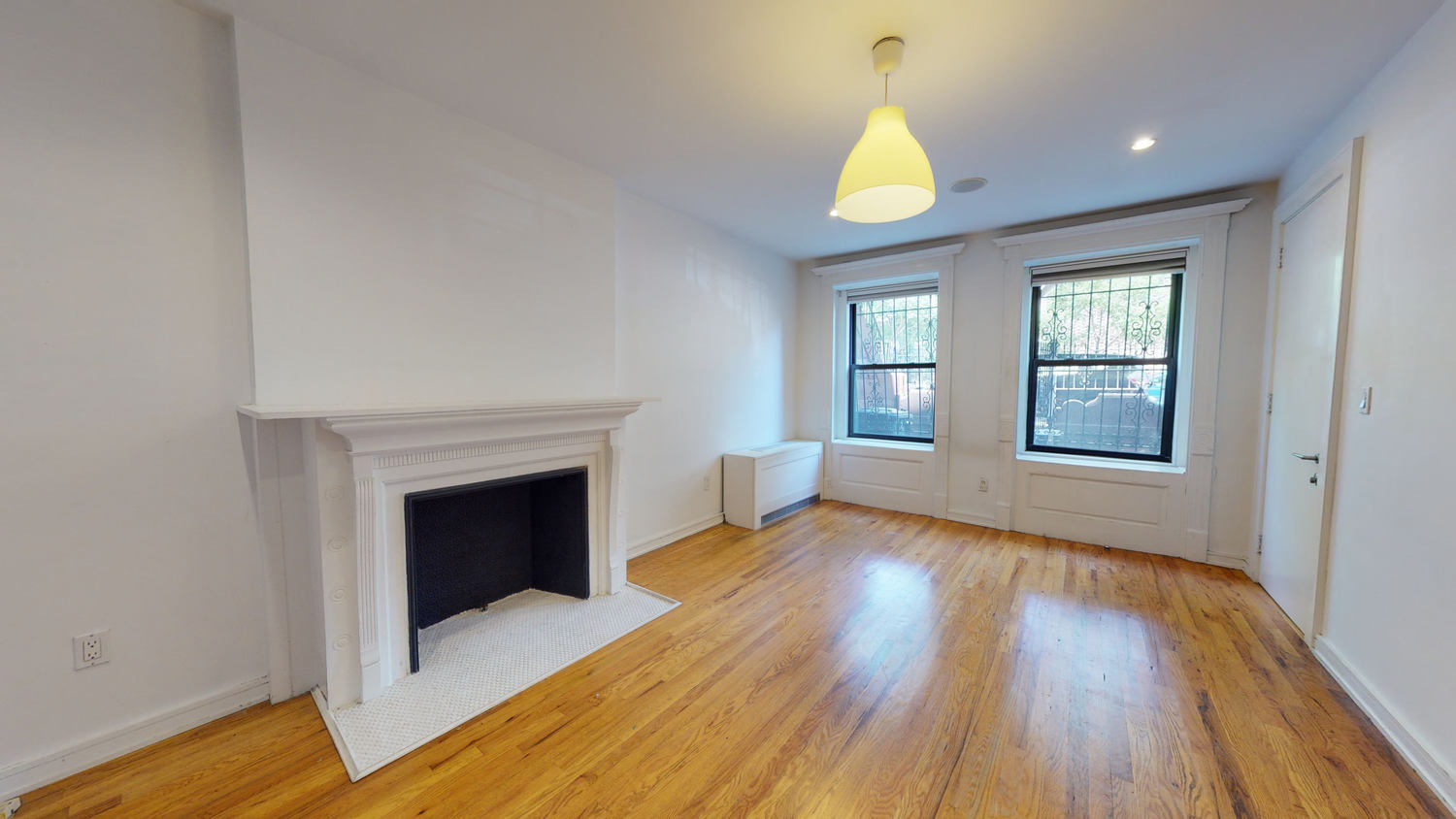 a view of an empty room with window and wooden floor