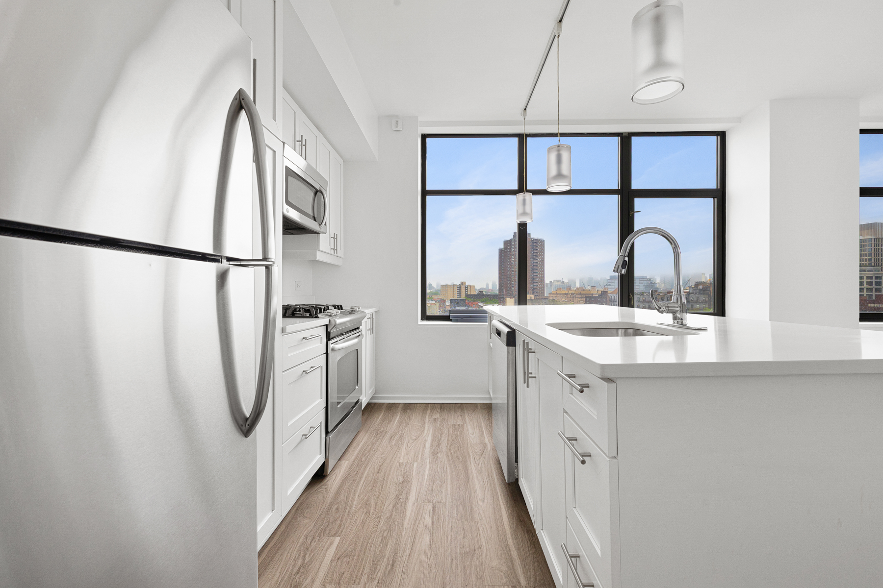 424 Bedford Avenue, Unit 6B Brooklyn, NY 11249 - Photo 3 of 11 a kitchen with a refrigerator a sink and dishwasher with wooden floor