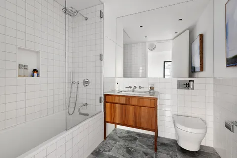 a bathroom with a granite countertop bathtub sink vanity mirror and toilet