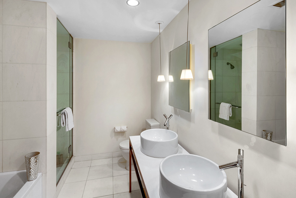 15 Broad Street, Unit 2506 Manhattan, NY 10005 - Photo 5 of 23 a bathroom with a toilet sink and mirror