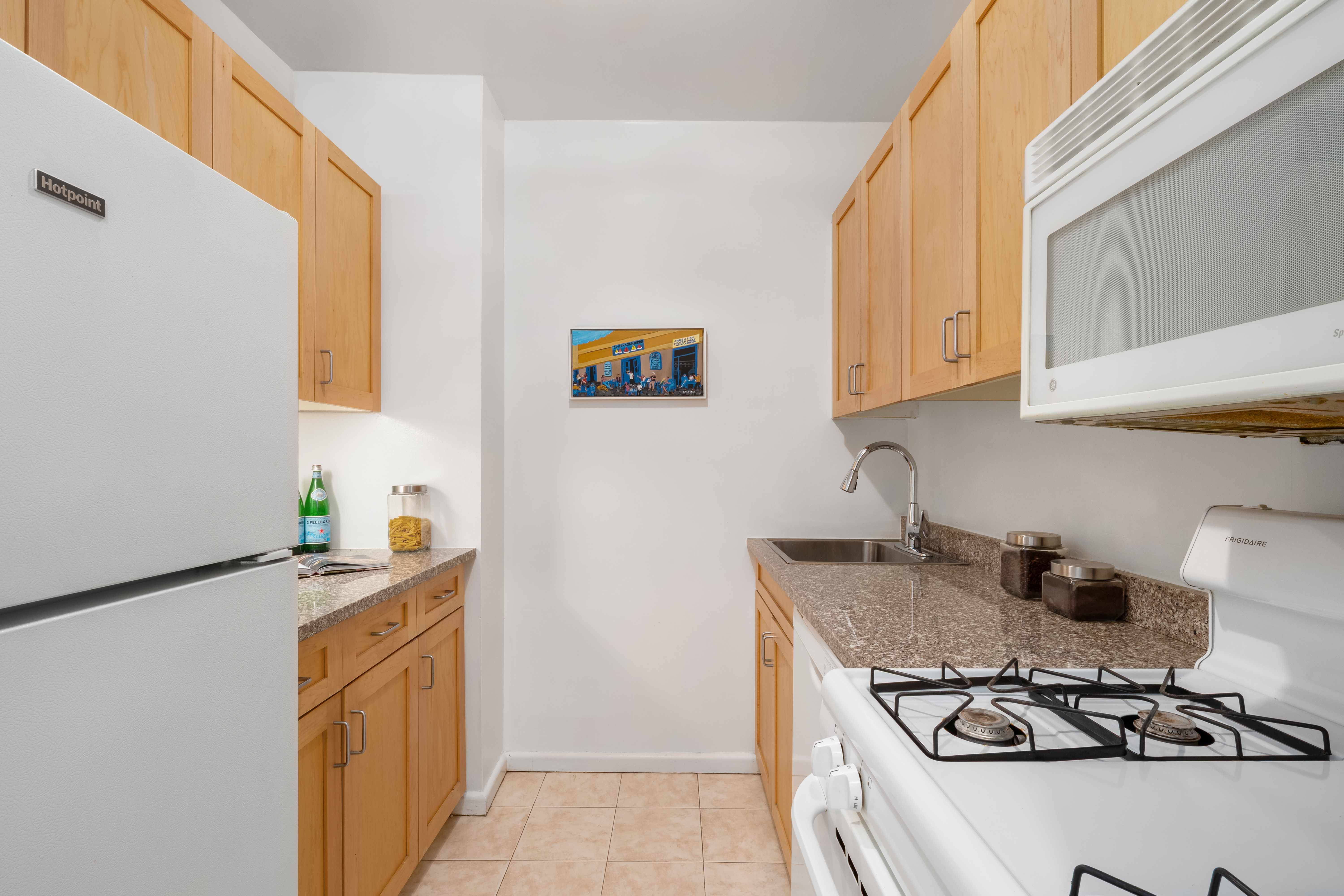 150 East 85th Street, Unit 3F Manhattan, NY 10028 - Photo 7 of 15 a kitchen with stainless steel appliances a stove a sink and a refrigerator