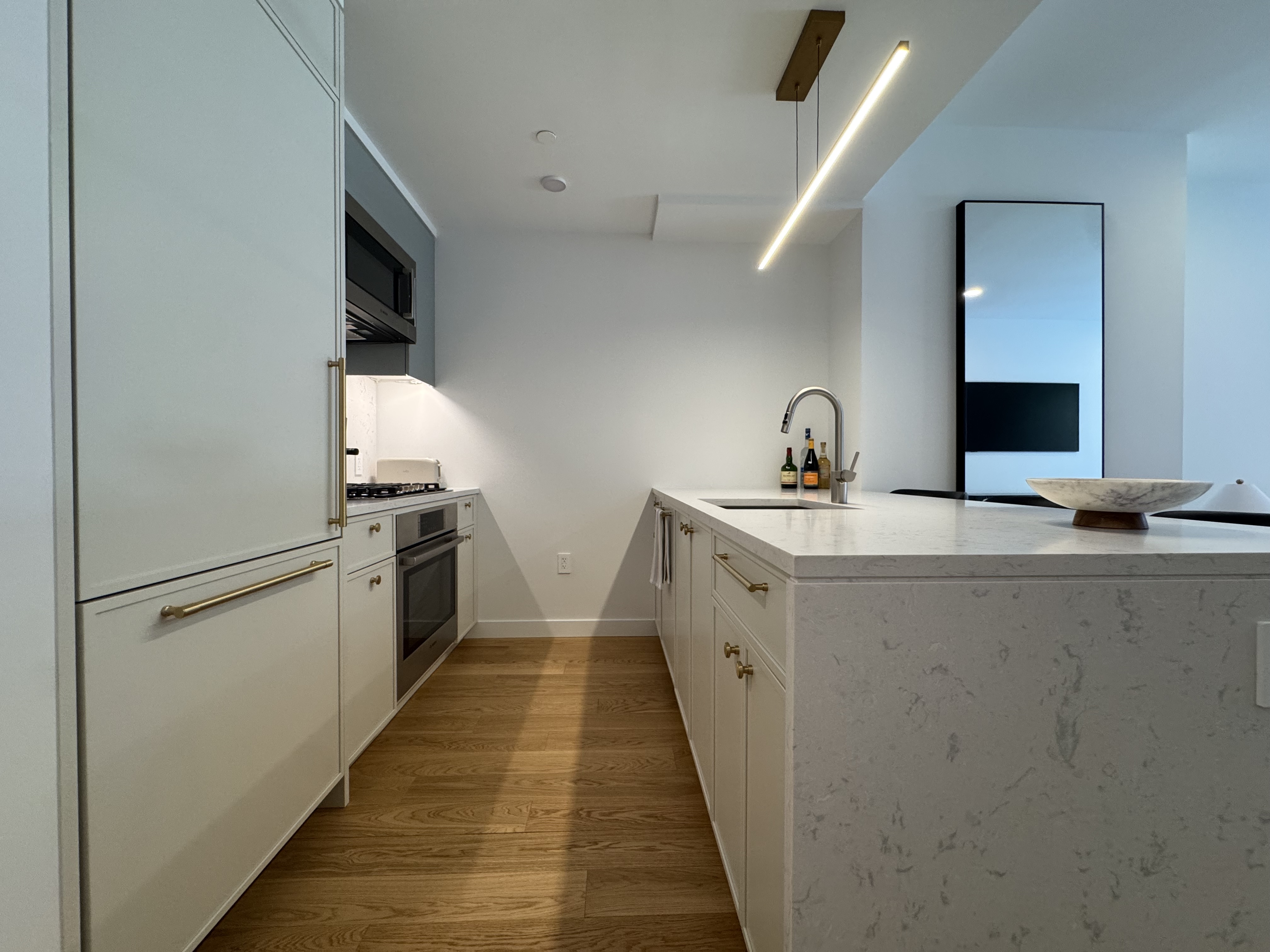 18 West 55th Street, Unit 7B Manhattan, NY 10019 - Photo 11 of 20 a kitchen with sink refrigerator and microwave