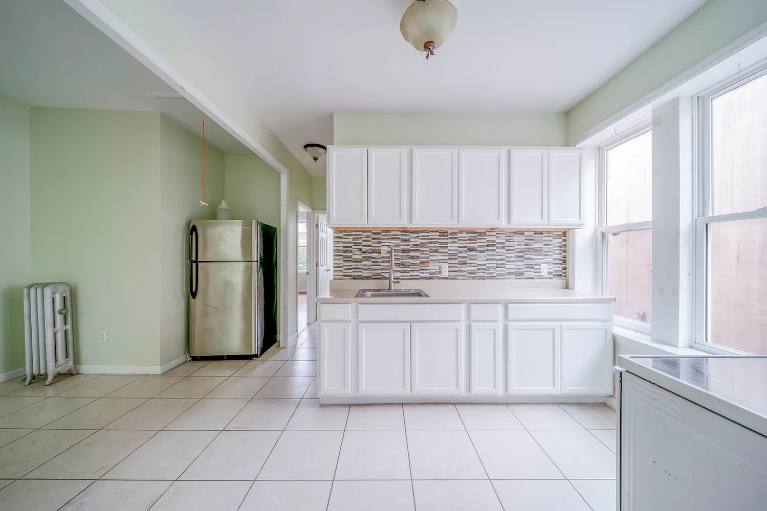 a kitchen with white cabinets and refrigerator