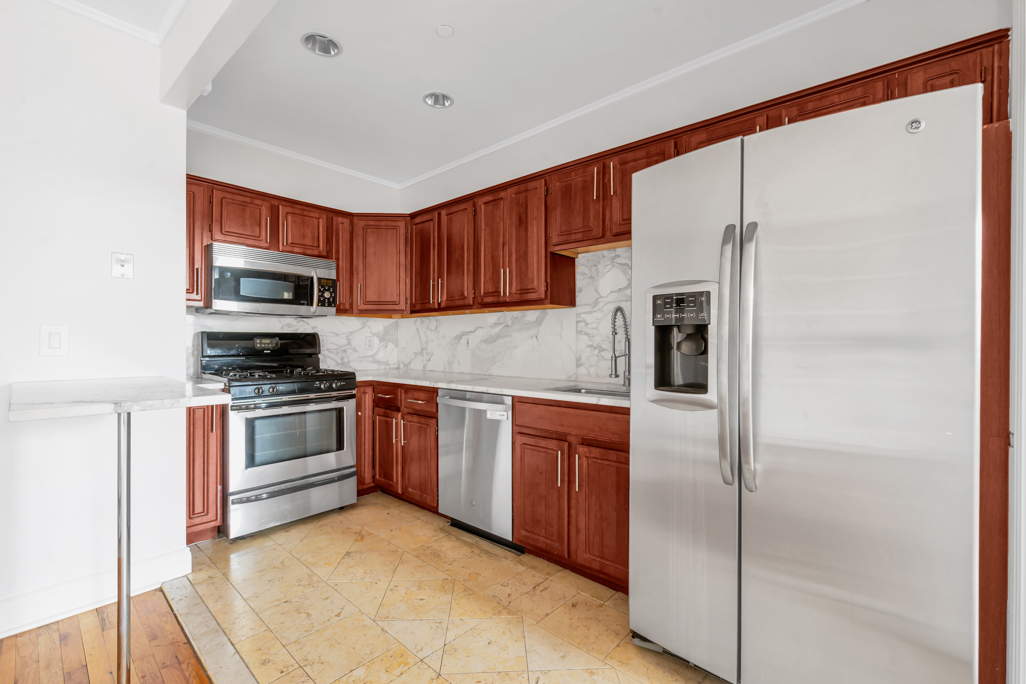 2098 Frederick Douglass Boulevard, Unit 5E Manhattan, NY 10026 - Photo 3 of 8 a kitchen with stainless steel appliances granite countertop a refrigerator sink and stove