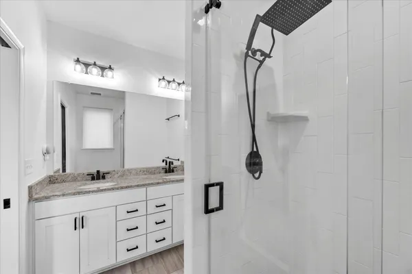 a bathroom with a granite countertop sink a mirror and shower