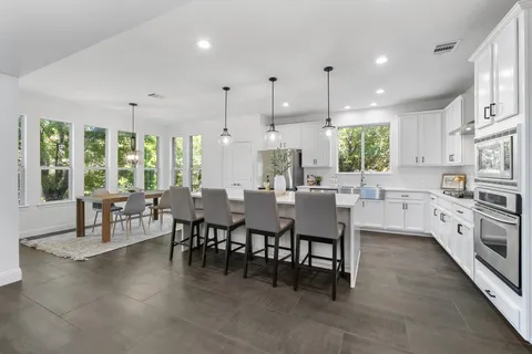 a large kitchen with lots of furniture a sink a dining table and chairs