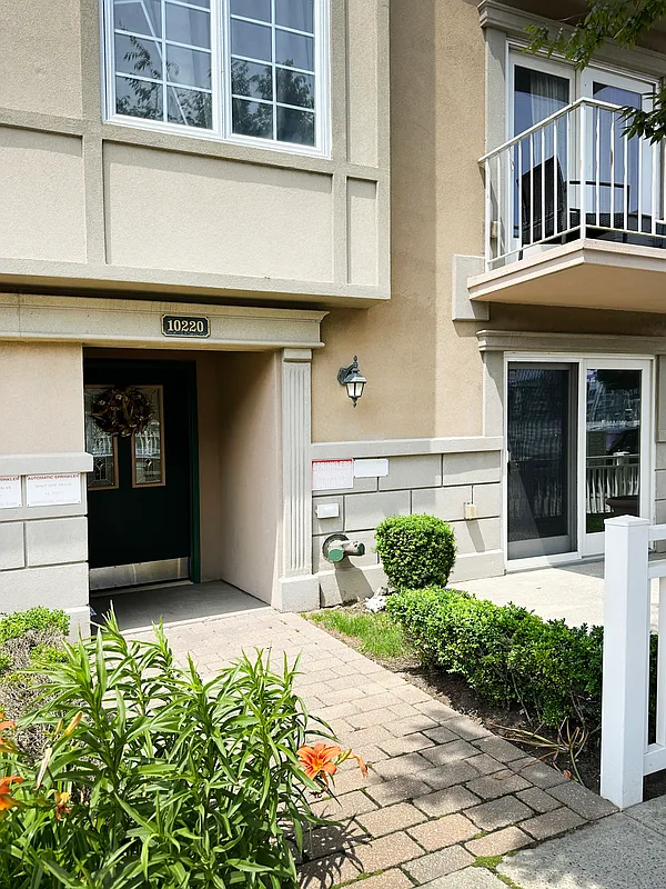 10220 Rockaway Beach Boulevard, Unit 1A Queens, NY 11694 - Photo 8 of 8 a front view of a house with a yard and potted plants