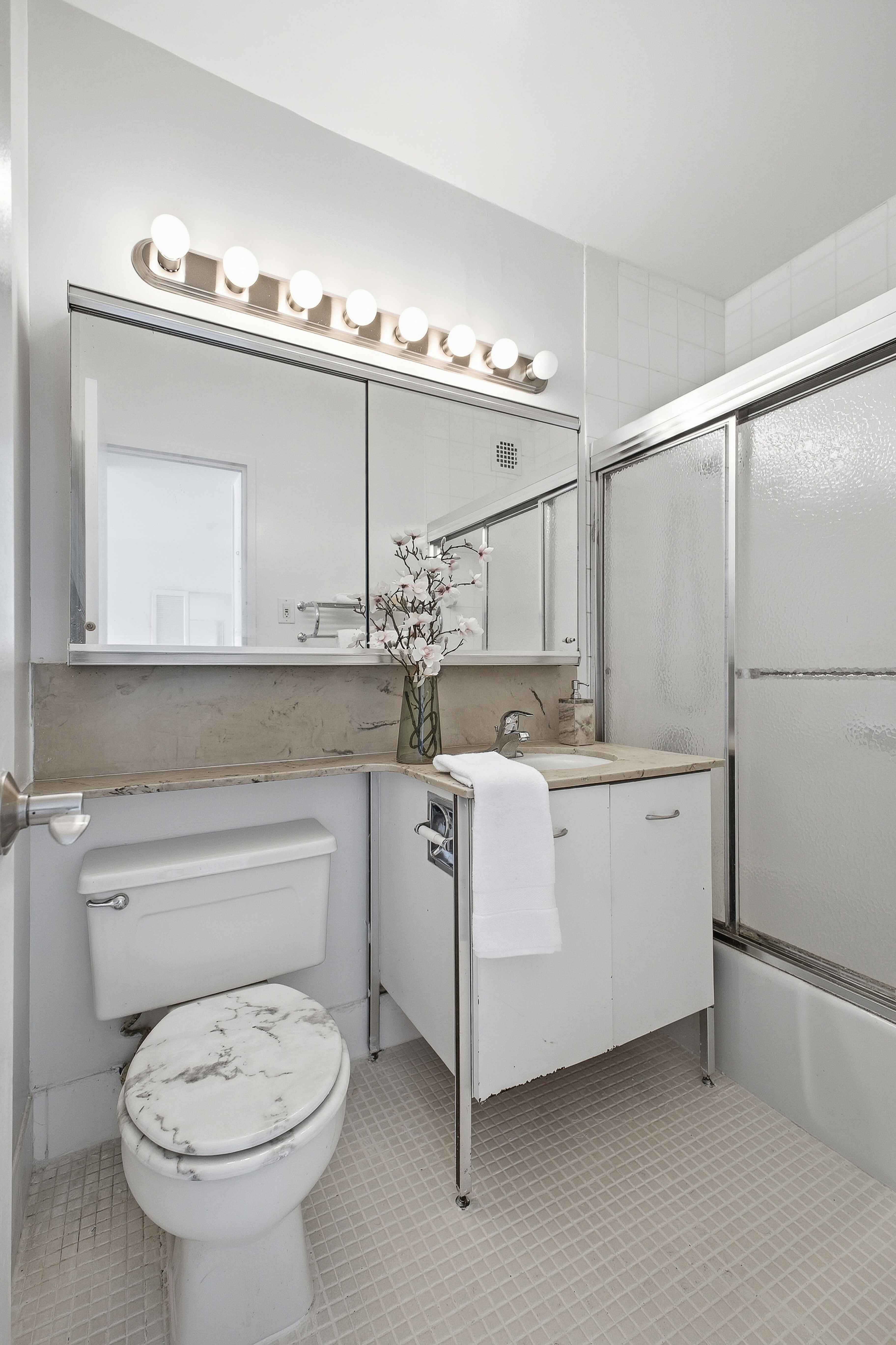 160 East 38th Street, Unit 26FG Manhattan, NY 10016 - Photo 10 of 23 a bathroom with a sink a toilet and mirror