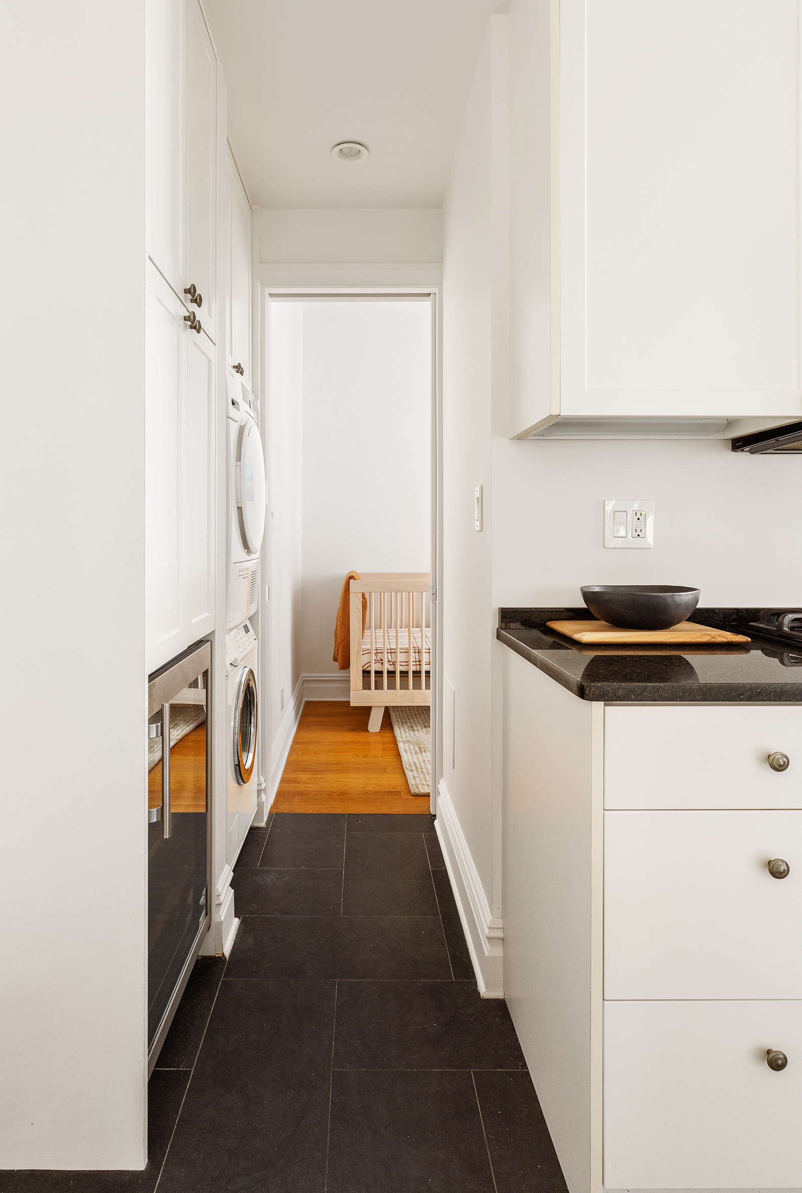 25 5th Avenue, Unit 9A Manhattan, NY 10003 - Photo 7 of 16 a hallway with a white stove top oven and a refrigerator with wooden floor