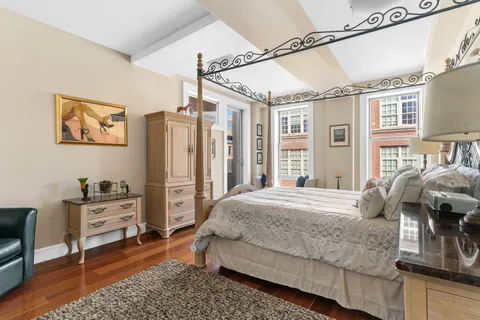 a bedroom with a bed dresser and wooden floor