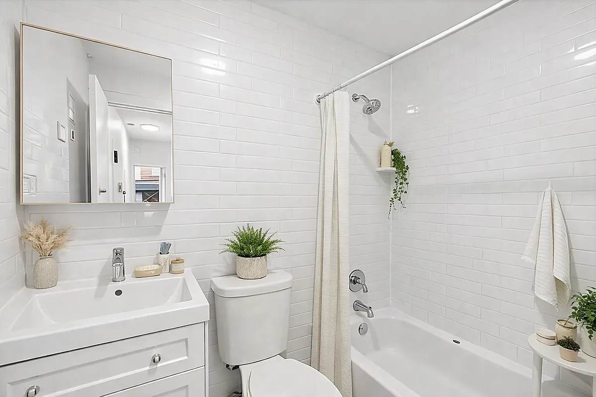 1260 Broadway, Unit 2F Brooklyn, NY 11221 - Photo 4 of 4 a bathroom with a sink a toilet a shower curtain and a bath tub