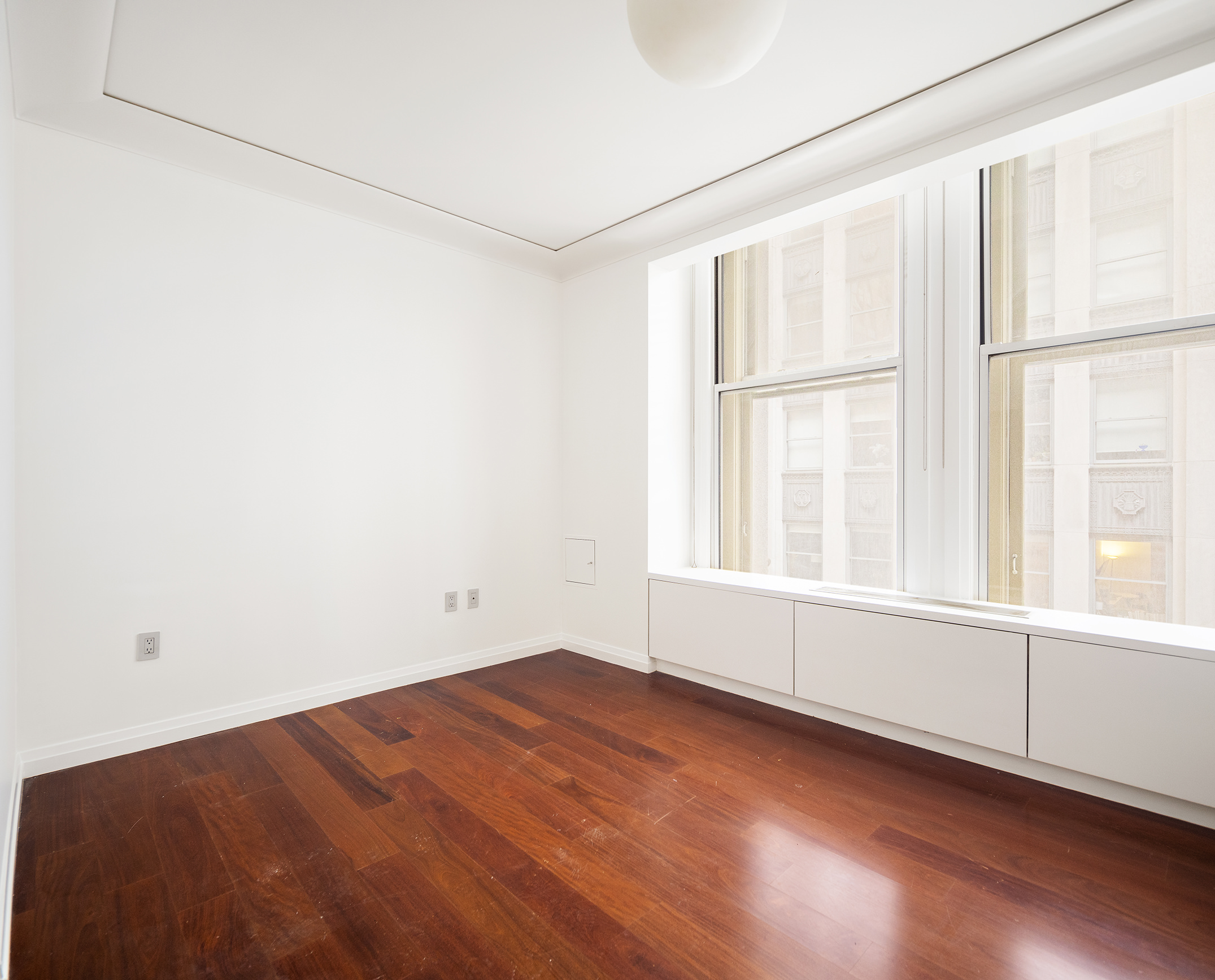 55 Wall Street, Unit 540 Manhattan, NY 10005 - Photo 6 of 10 an empty room with wooden floor and windows