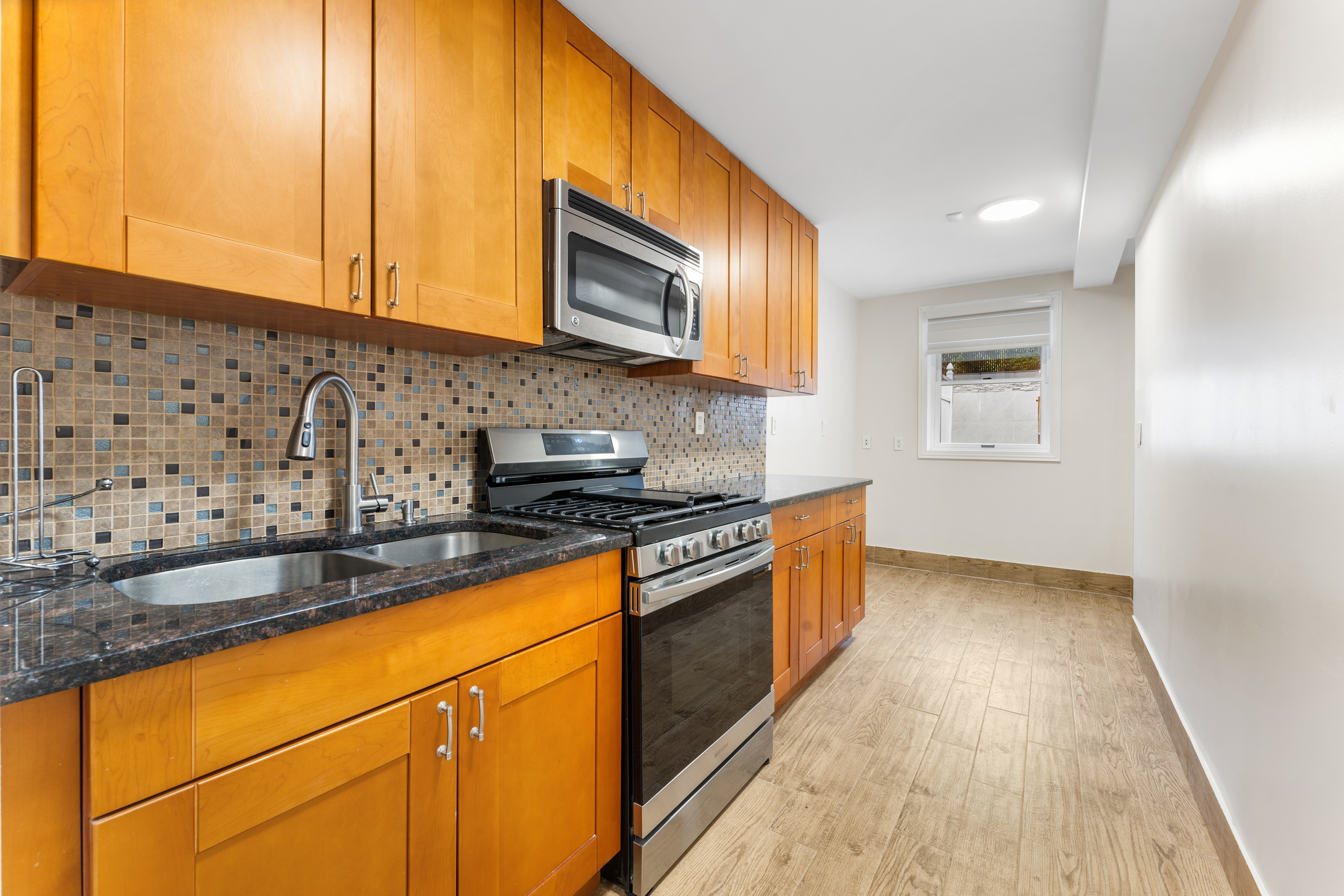 149 Pembroke Street, Unit B Brooklyn, NY 11235 - Photo 2 of 6 a kitchen with granite countertop wooden cabinets stainless steel appliances and a sink