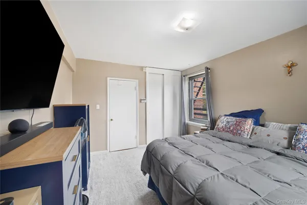 a bedroom with a bed and a flat tv screen on dresser