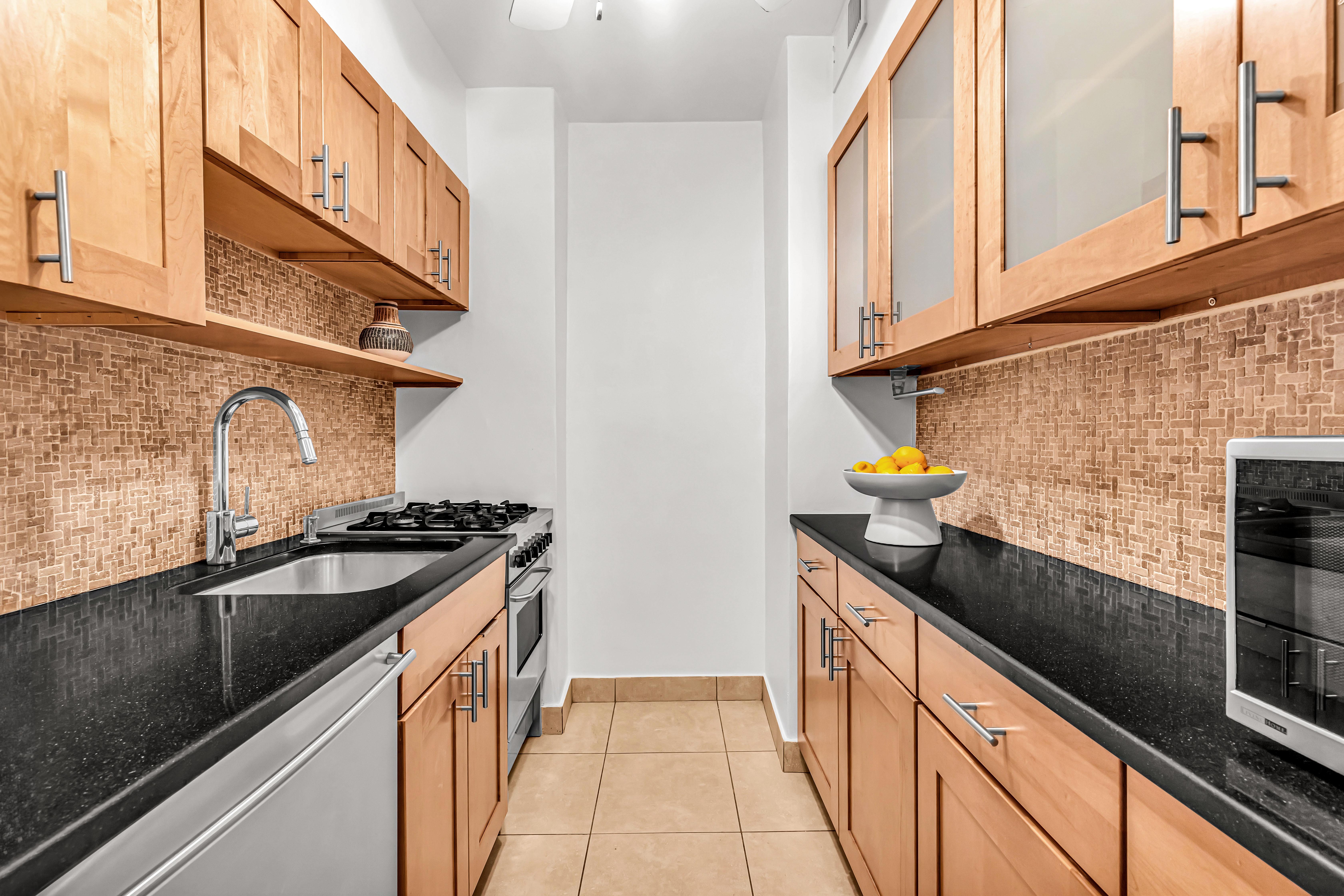 203 East 72nd Street, Unit 3E Manhattan, NY 10021 - Photo 3 of 6 a kitchen with granite countertop a sink and stove