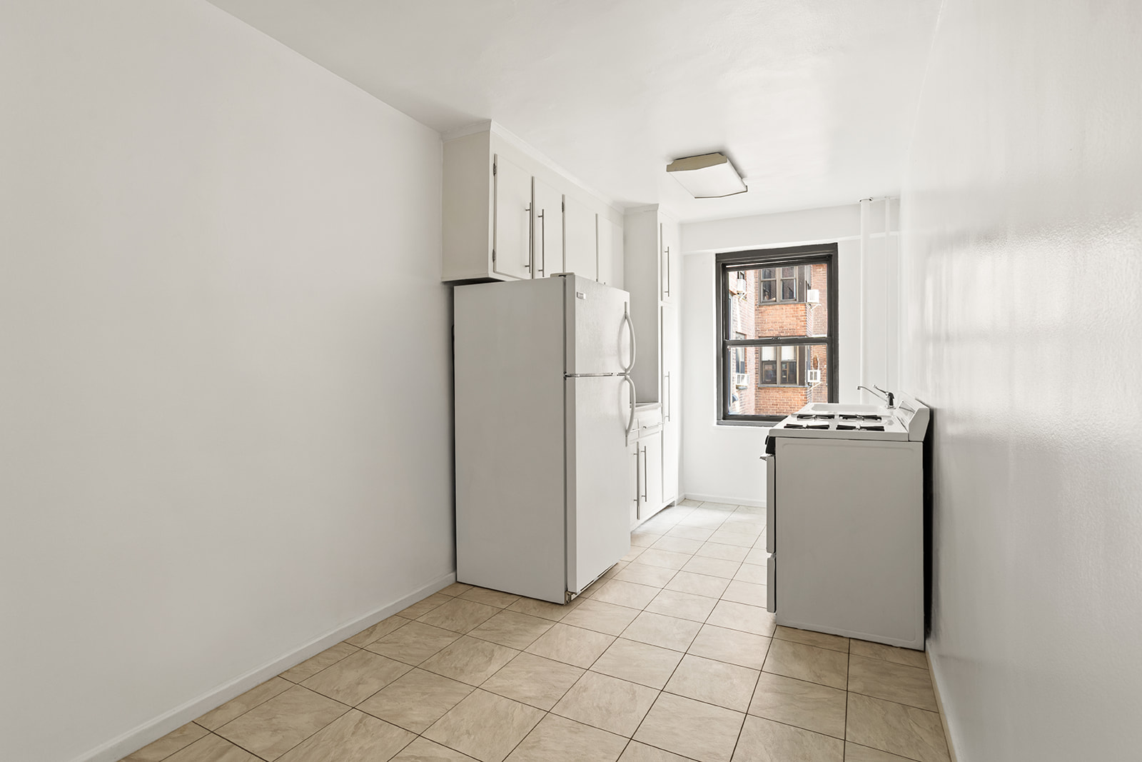 385 Grand Street, Unit L207 Manhattan, NY 10002 - Photo 4 of 12 a view of a kitchen with refrigerator and window