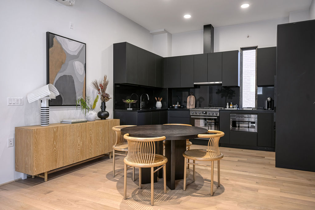 459 Harman Street, Unit 1 Manhattan, NY 10026 - Photo 4 of 17 a kitchen with stainless steel appliances kitchen island granite countertop a table chairs and a refrigerator