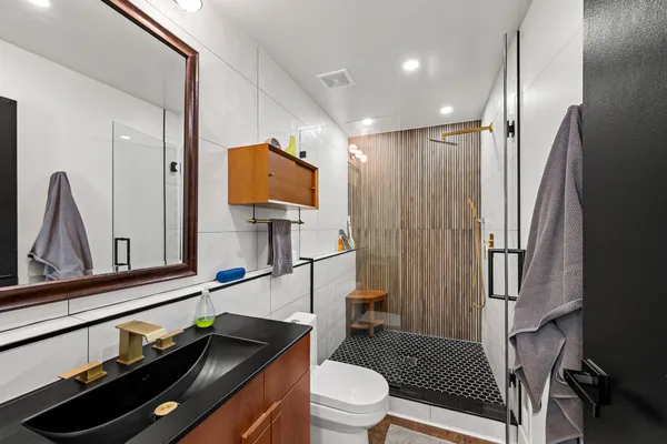 a bathroom with a sink a toilet a mirror and shower