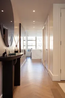 a living room with couches chairs and kitchen view with wooden floor