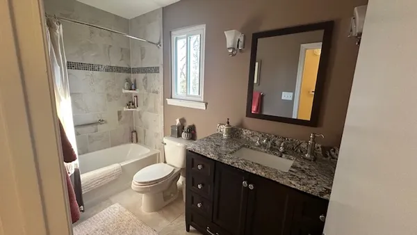 a bathroom with a granite countertop sink toilet and shower