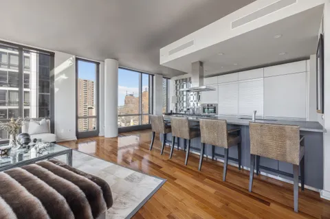 a living room with furniture a large window and wooden floor