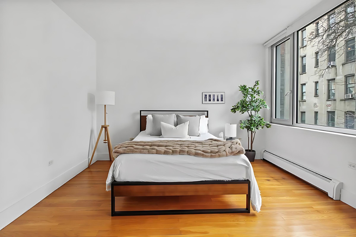 154 Attorney Street, Unit 304 Manhattan, NY 10002 - Photo 6 of 13 a bedroom with a bed potted plant and wooden floor