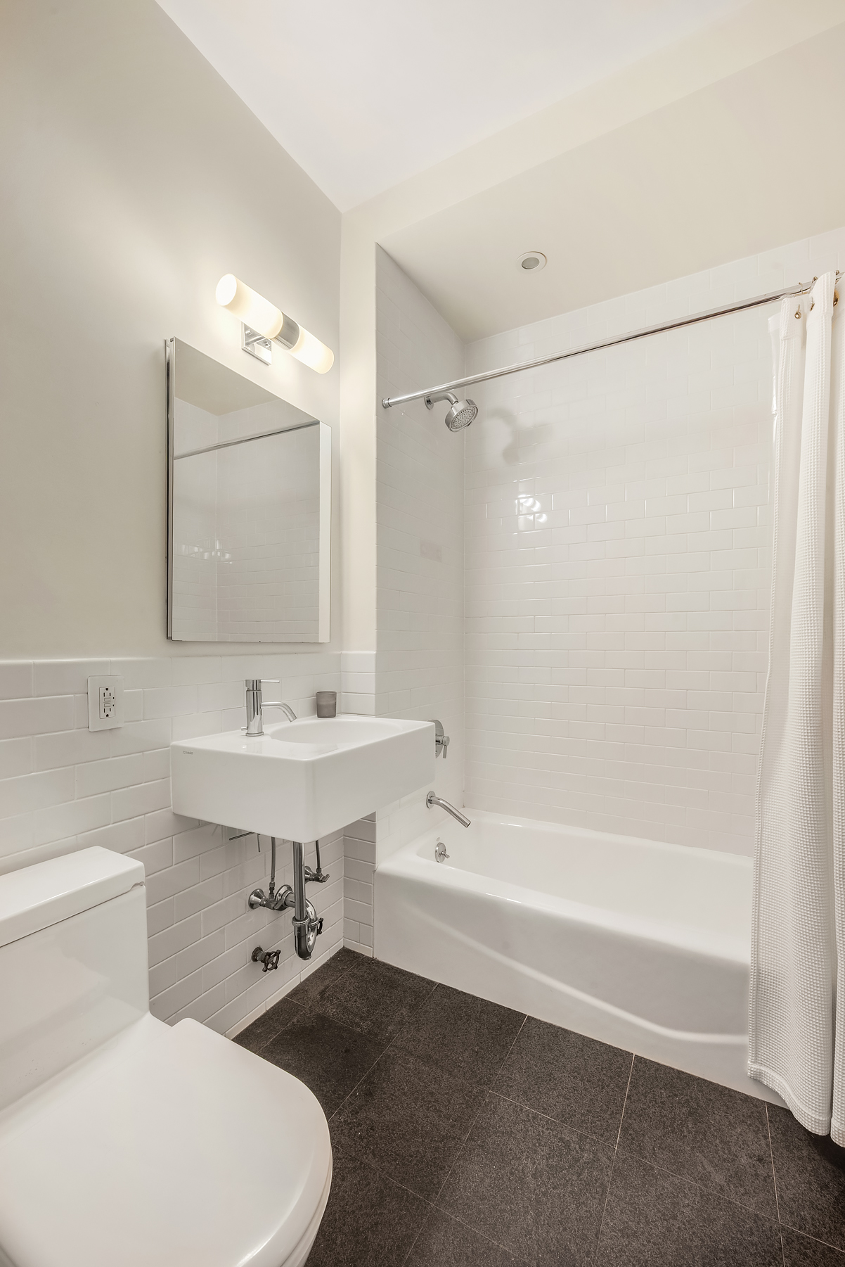 175 East Broadway, Unit 4C Manhattan, NY 10002 - Photo 9 of 14 a bathroom with a sink toilet a mirror and shower