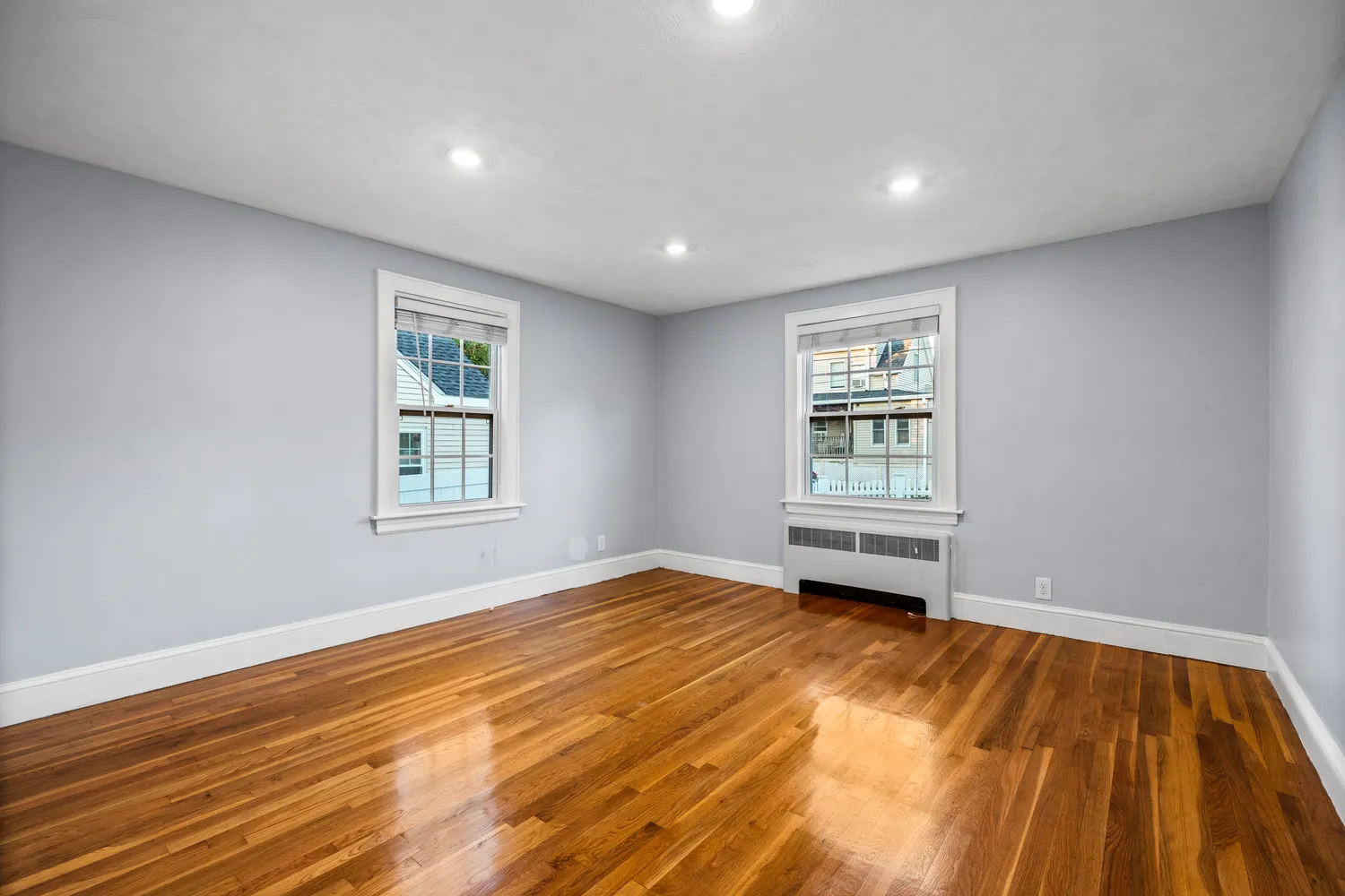a view of an empty room with a window and wooden floor