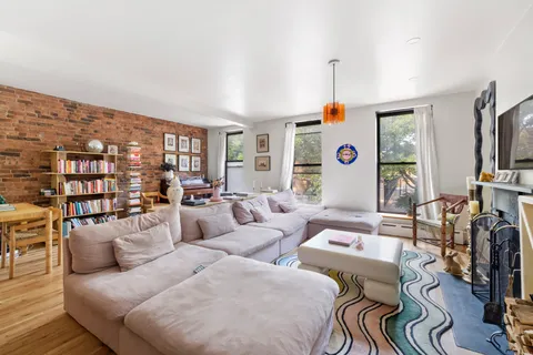 a living room with furniture a flat screen tv and a book shelf
