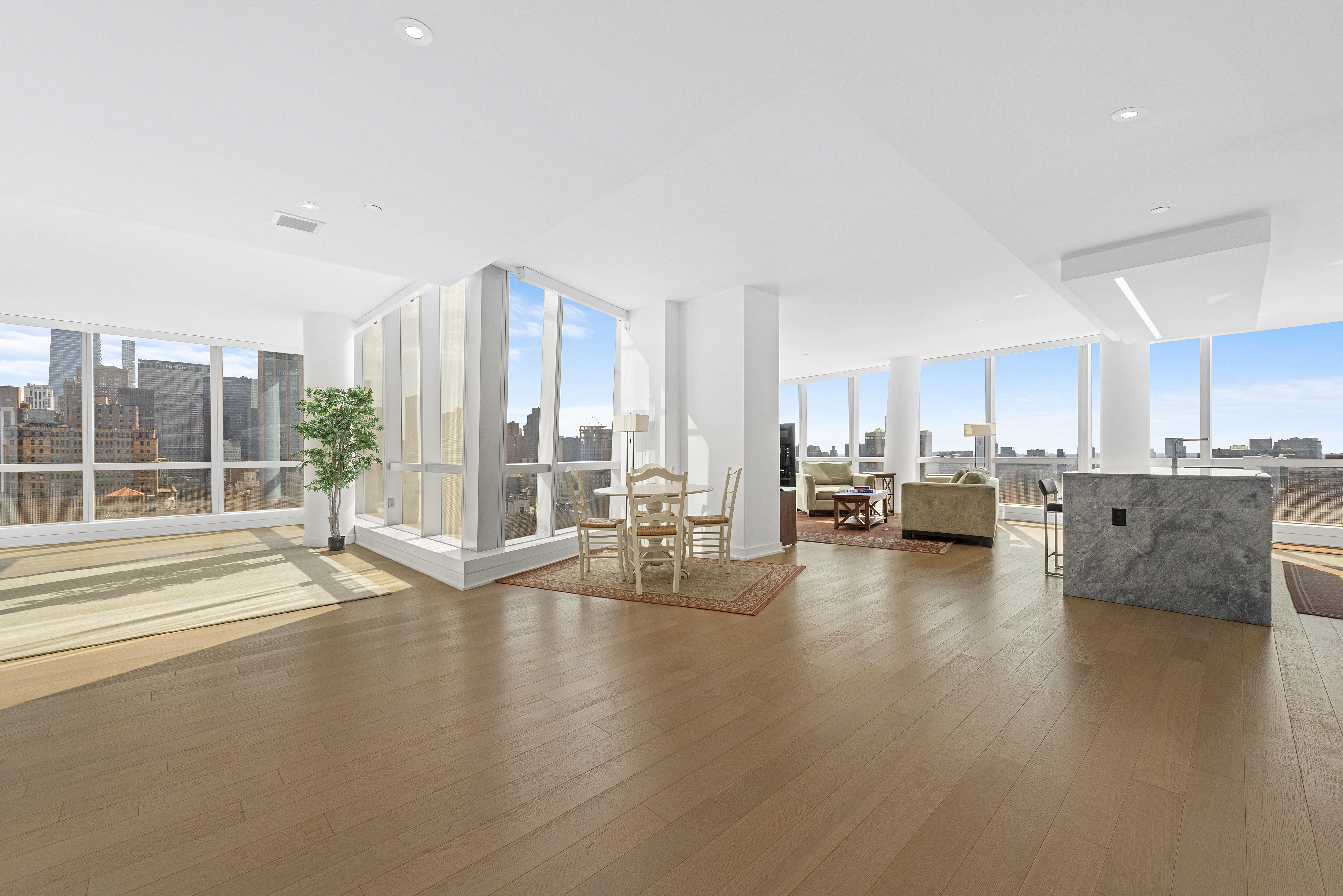a living room with couches and kitchen view with wooden floor
