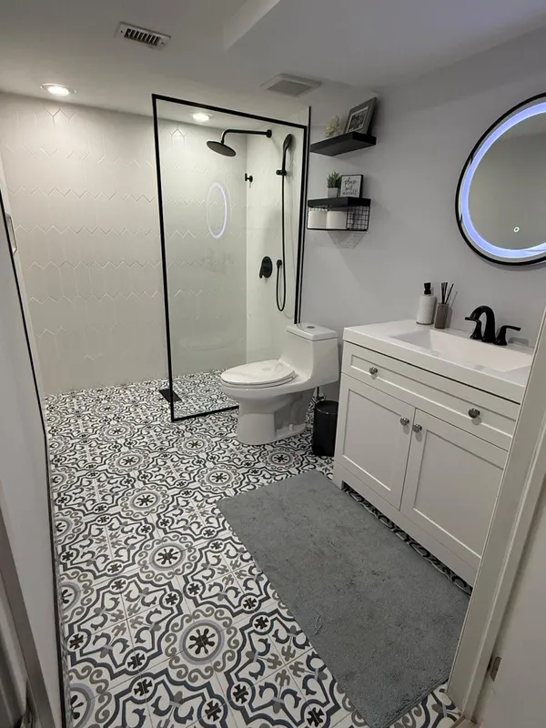 a bathroom with a sink a toilet a mirror and shower