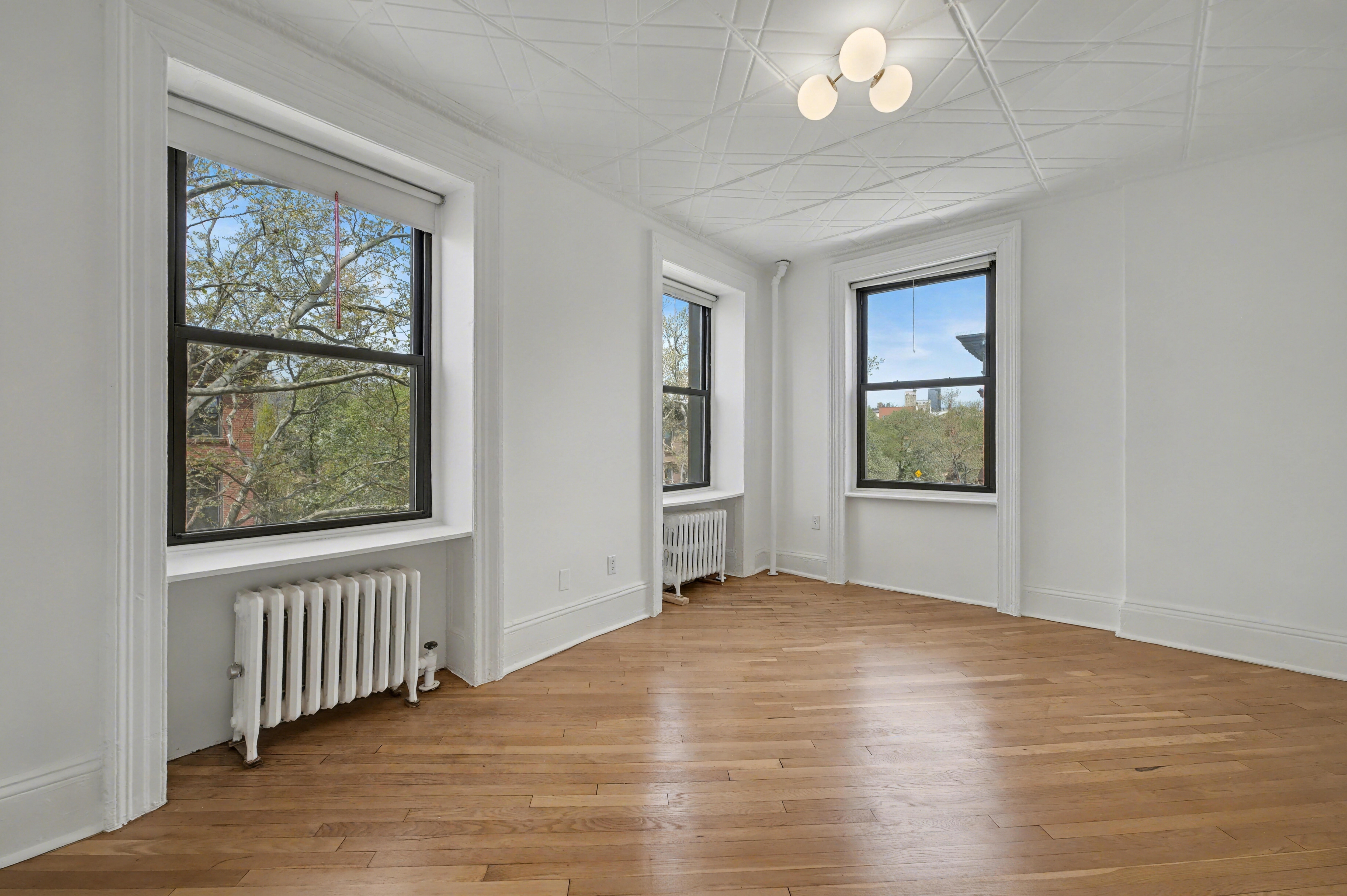 261 Clinton Street, Unit 3 Brooklyn, NY 11201 - Photo 5 of 12 a view of an empty room with wooden floor and a window