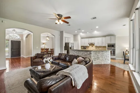 a living room with furniture kitchen view and a wooden floor