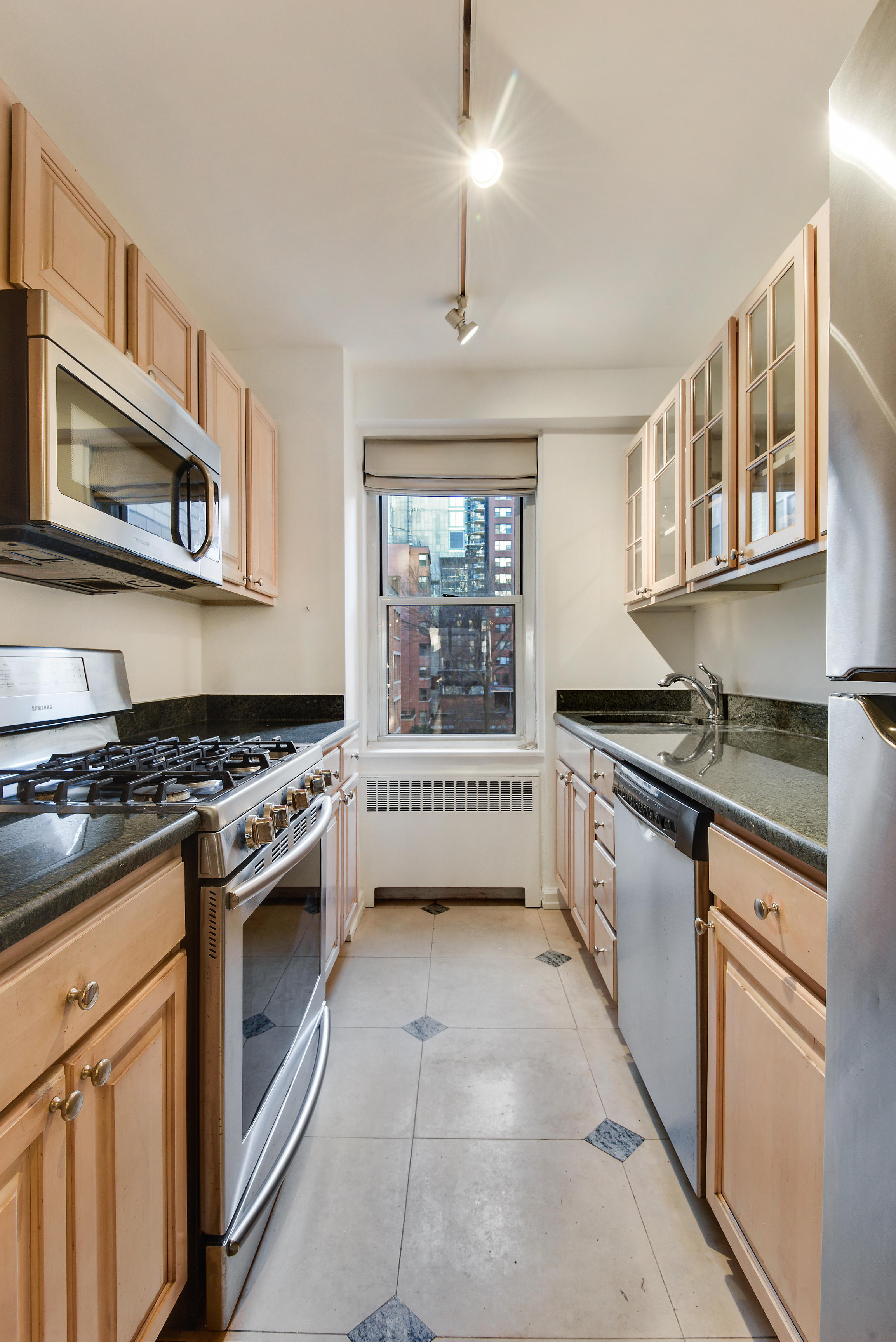 150 East 61st Street, Unit 5C Manhattan, NY 10065 - Photo 8 of 18 a kitchen with stainless steel appliances granite countertop a stove and a sink