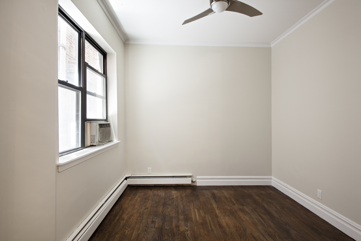 442 Amsterdam Avenue, Unit 4C Manhattan, NY 10024 - Photo 8 of 9 an empty room with wooden floor and windows