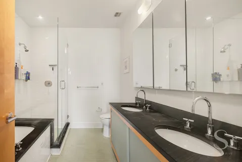 a bathroom with a sink double vanity granite tub shower and a mirror