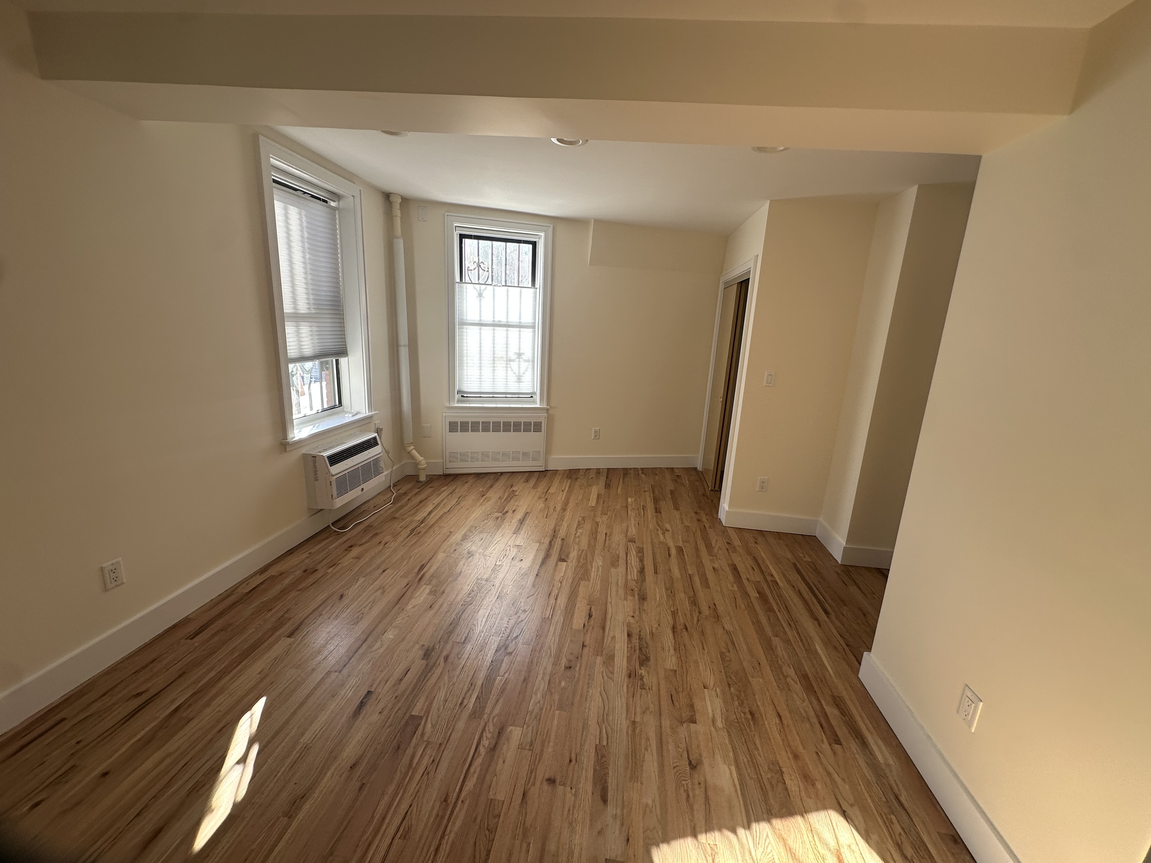 752 Greenwich Street, Unit 1A/B Manhattan, NY 10014 - Photo 2 of 12 an empty room with wooden floor and windows