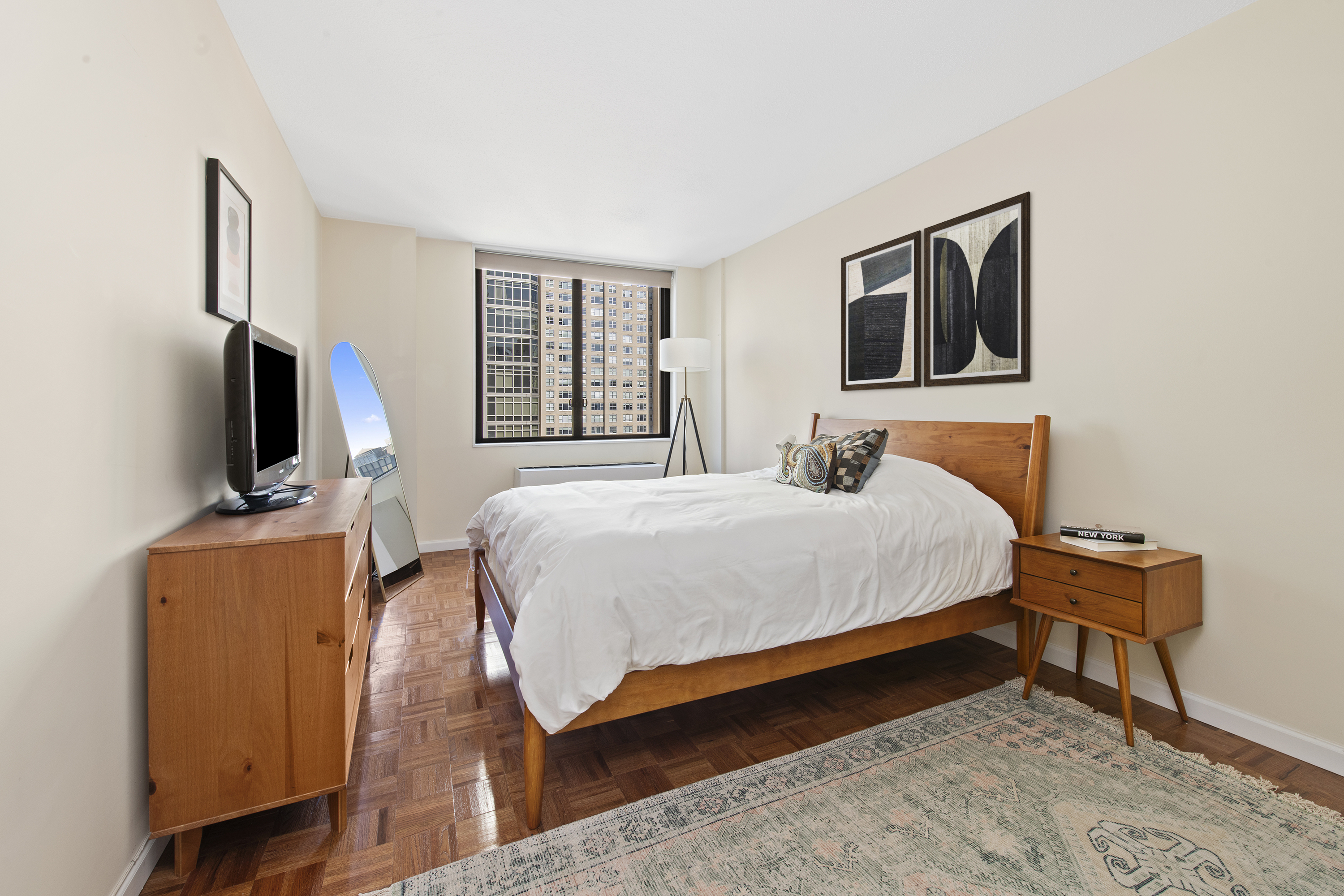 300 East 54th Street, Unit 23J Manhattan, NY 10022 - Photo 3 of 18 a bedroom with a bed a flat screen tv and dresser