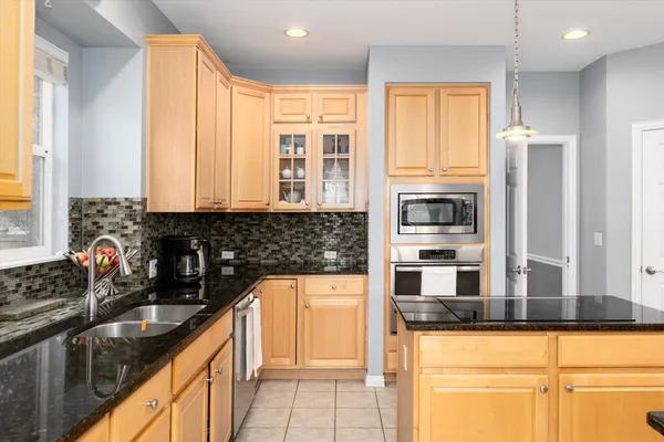 a kitchen with stainless steel appliances granite countertop a sink a stove and a wooden cabinets