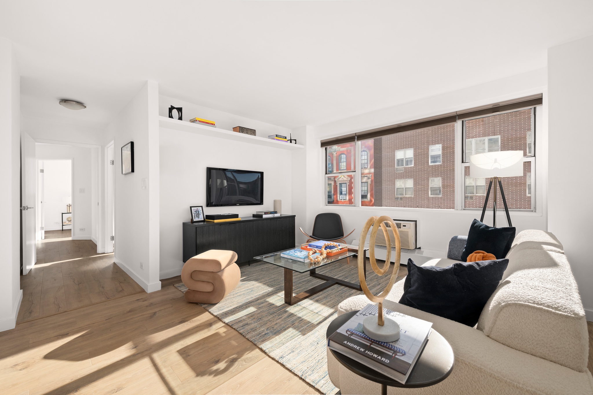 79 West 12th Street, Unit 6BC Manhattan, NY 10011 - Photo 2 of 15 a living room with furniture a flat screen tv and a floor to ceiling window