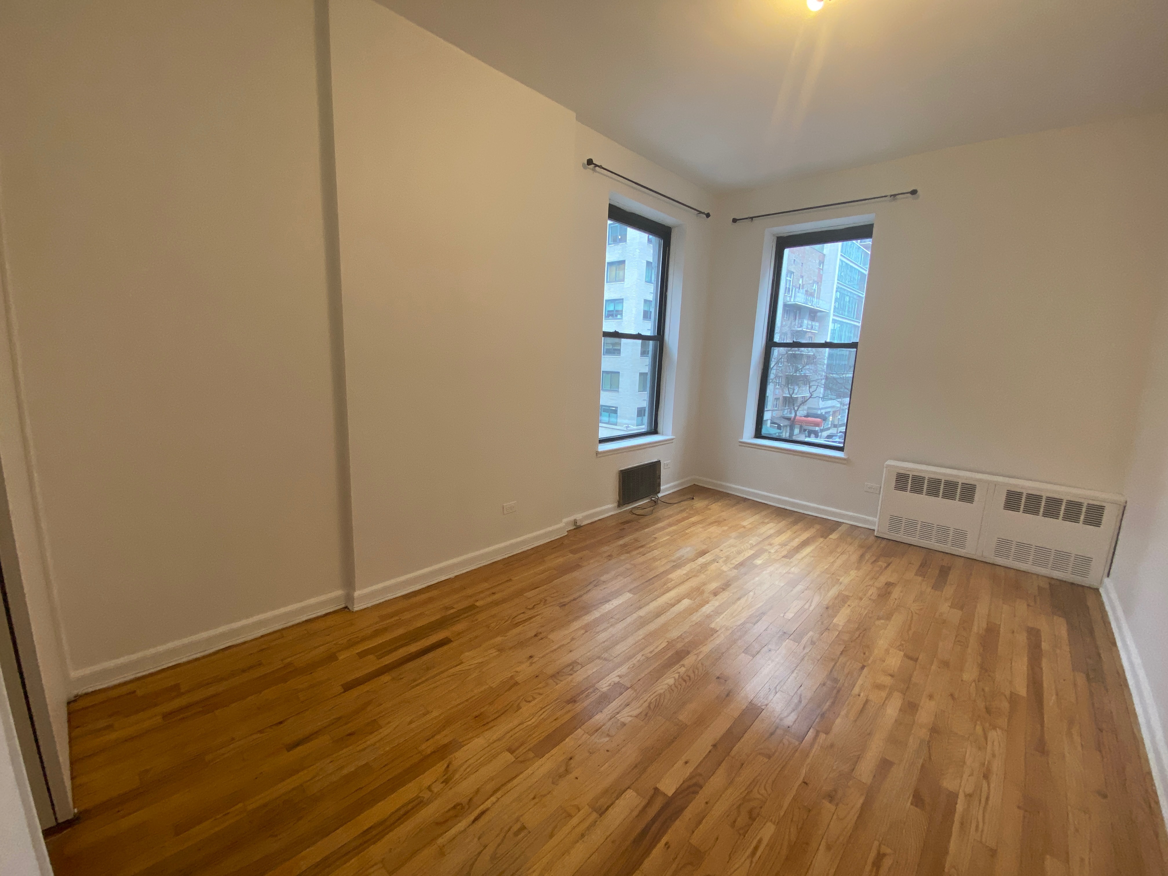 1240 Lexington Avenue, Unit 34 Manhattan, NY 10028 - Photo 7 of 11 an empty room with wooden floor and windows