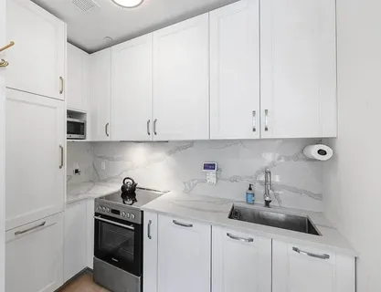 a kitchen with white cabinets and sink